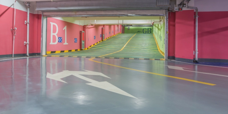 Rampa de acceso a parking subterráneo con pavimento antideslizante y franjas amarillas de seguridad