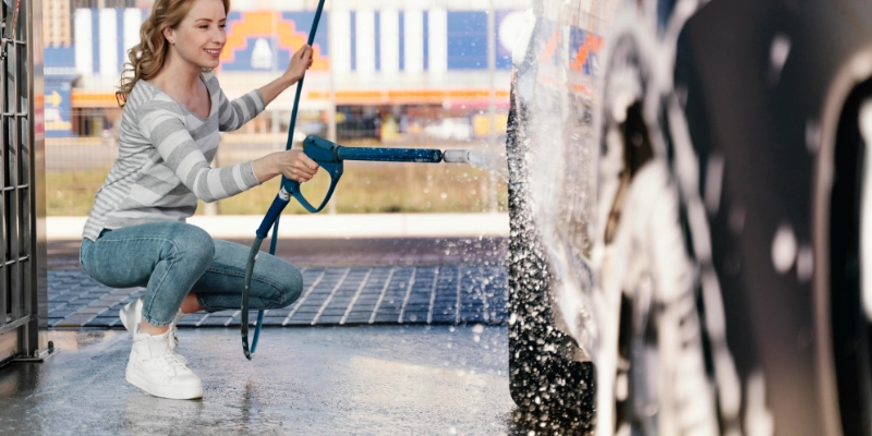 Mujer lavando coche en zona exterior con pavimento impermeable y drenaje eficiente